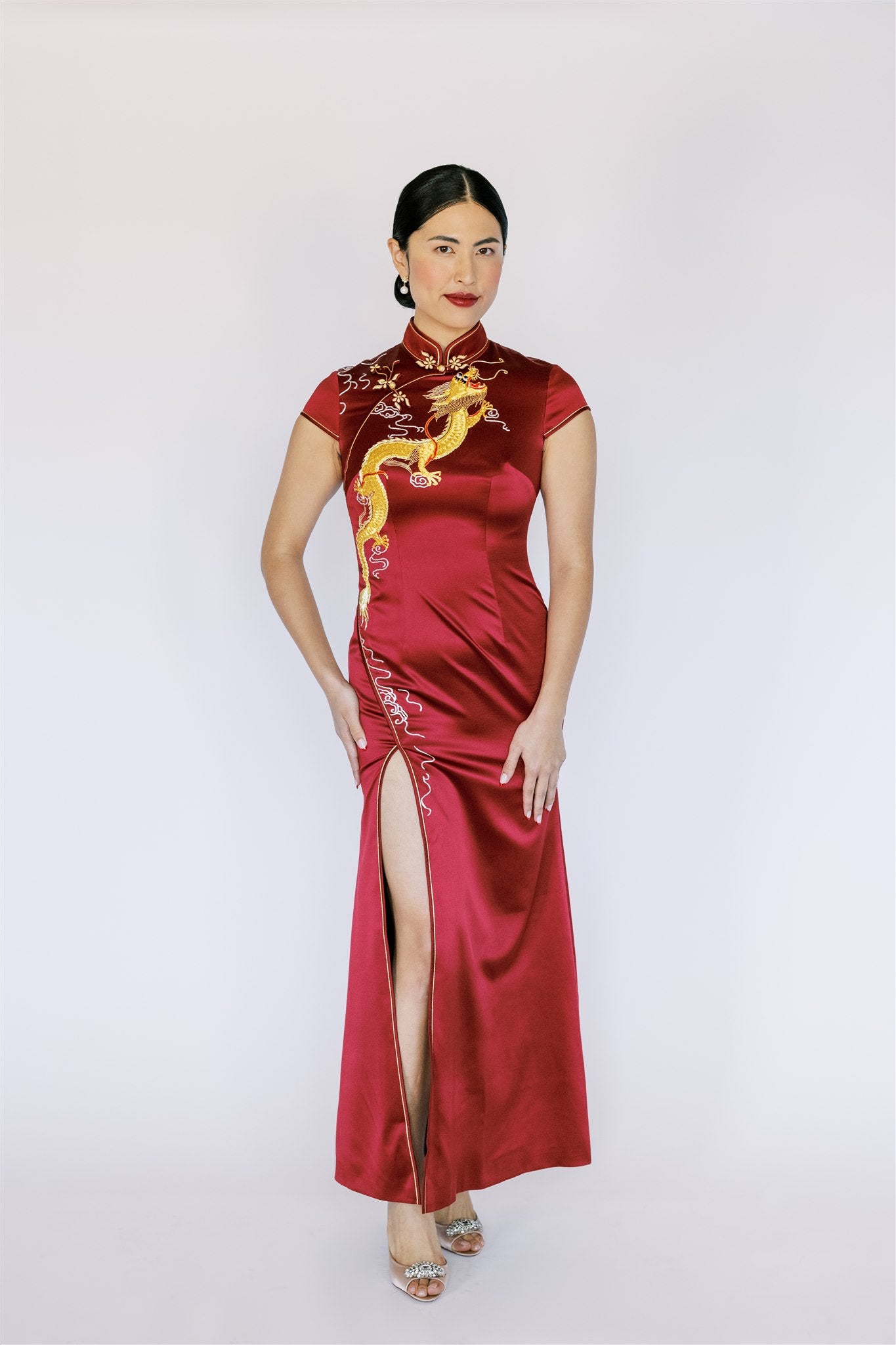 A woman wearing a modern wine red silk Qipao with gold dragon and slit