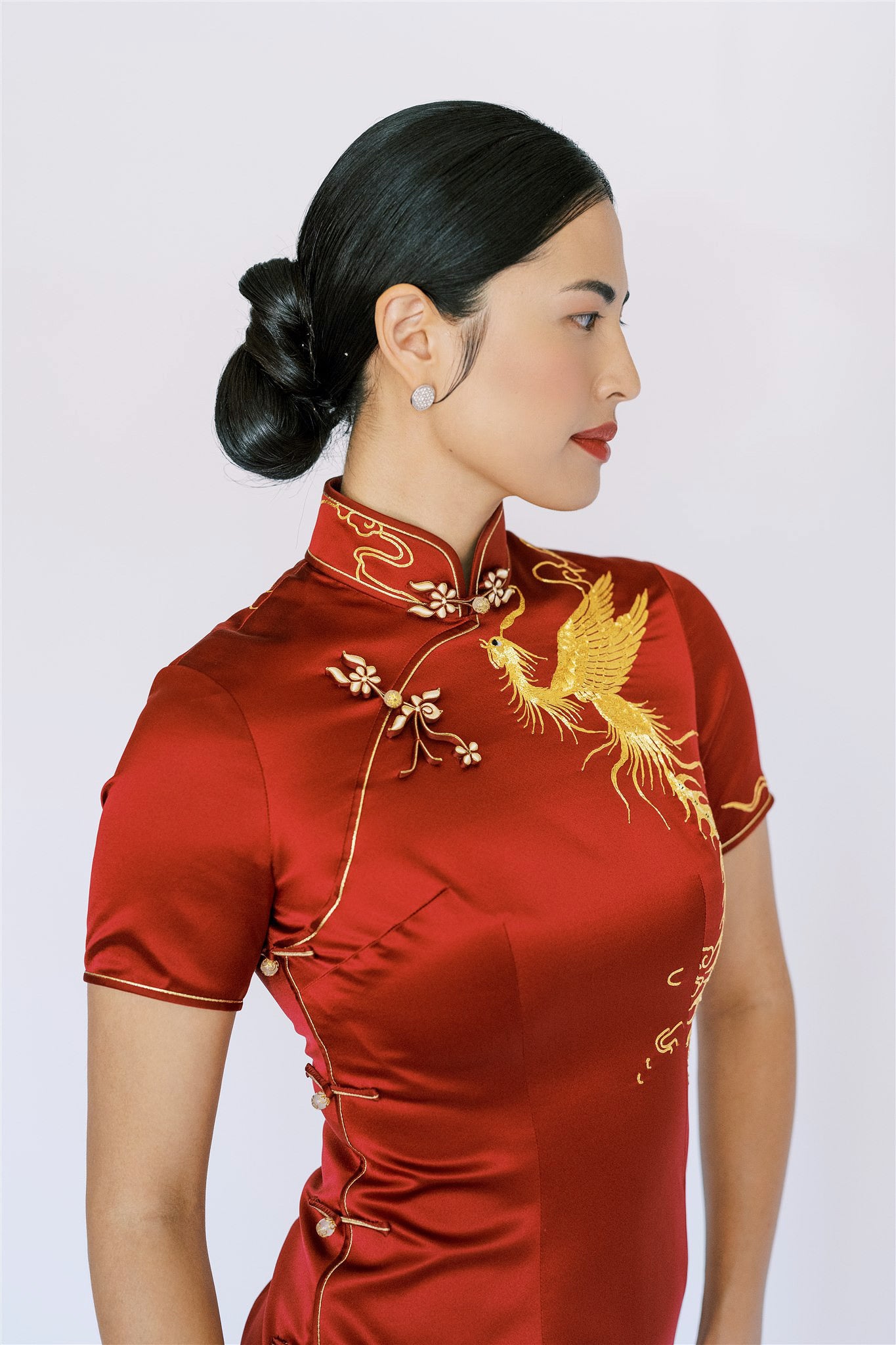 A woman wearing wine red wedding qipao with gold phoenix