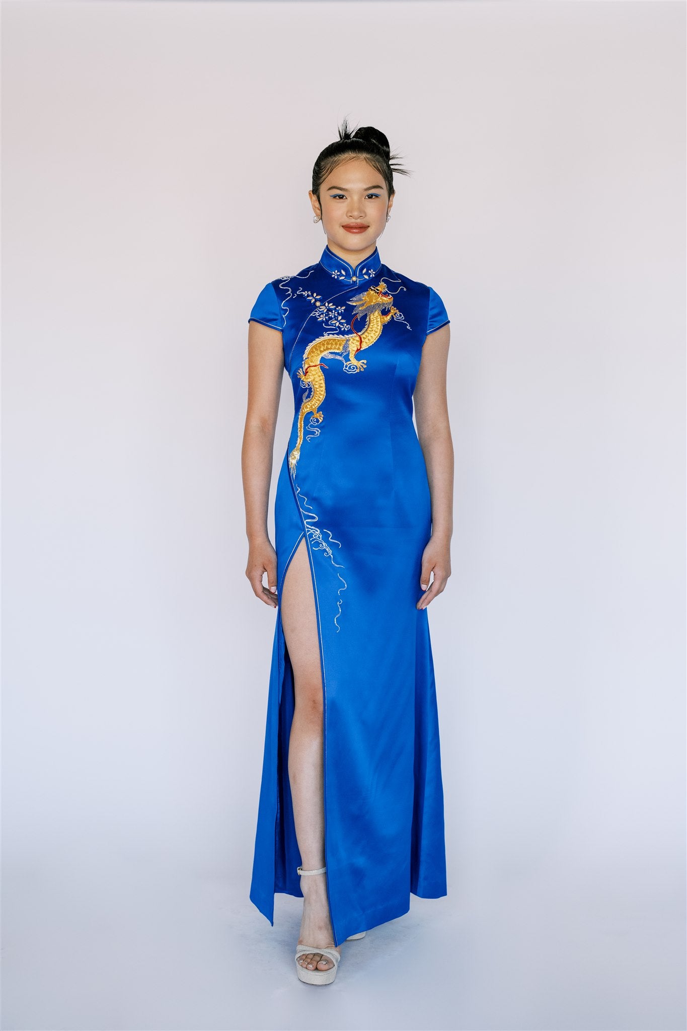 Front view of a woman wearing a  royal blue mermaid modern Cheongsam dress with front slit, a gold dragon embroidery.