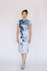 A front view of a stylish short blue silk Qipao featuring luxurious velvet floral applique, ideal for special occasions.