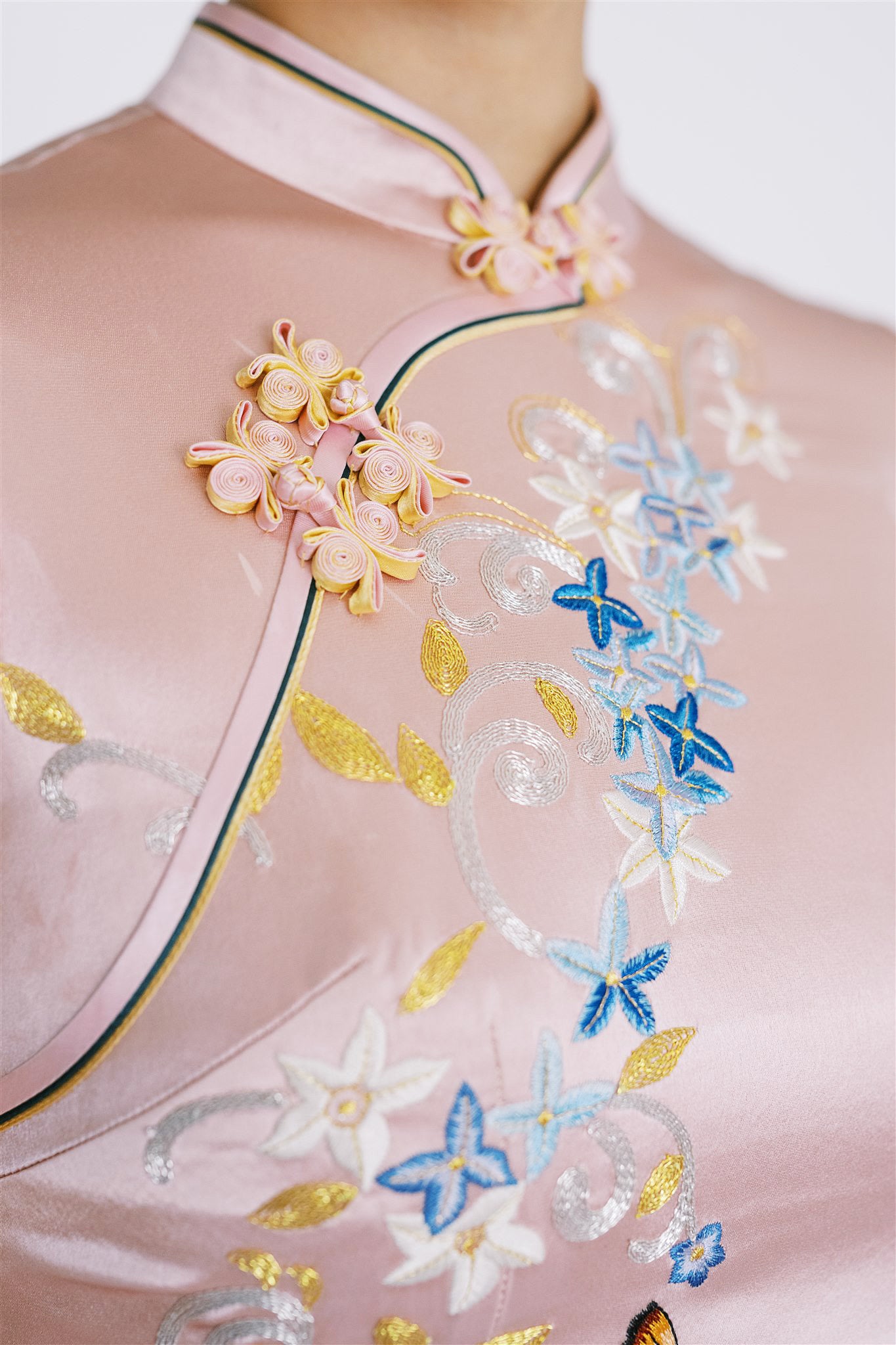 Close-up of floral embroidery and butterfly Pankou details on pink Cheongsam.