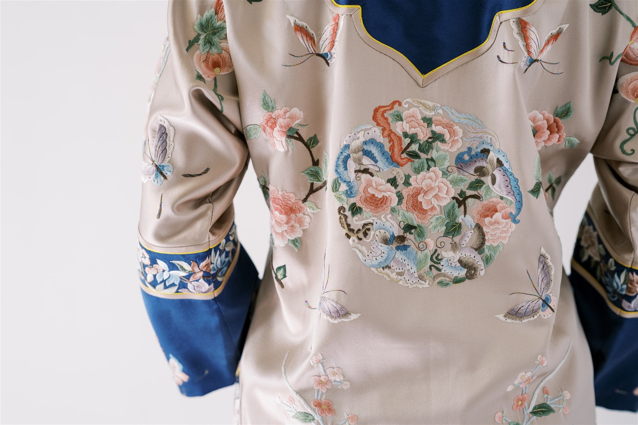 A woman wearing silver and blue tang jacket with floral, peony and butterflies