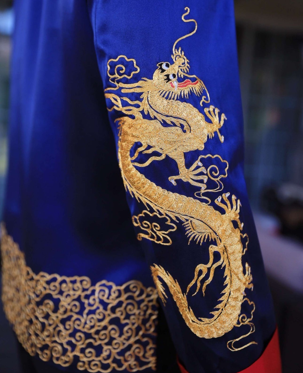 Details of hand-embroidered gold dragon on the sleeve of a navy blue silk tang suit. 