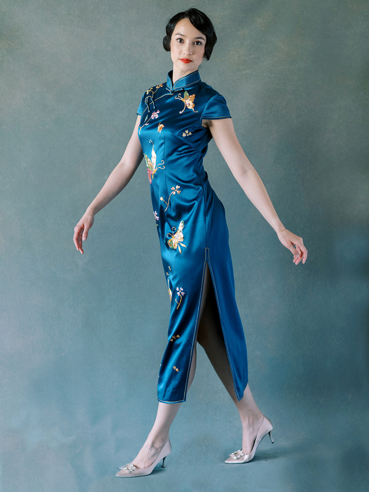 Embroidery detail of butterfly and blooming peonies on teal silk Qipao dress.