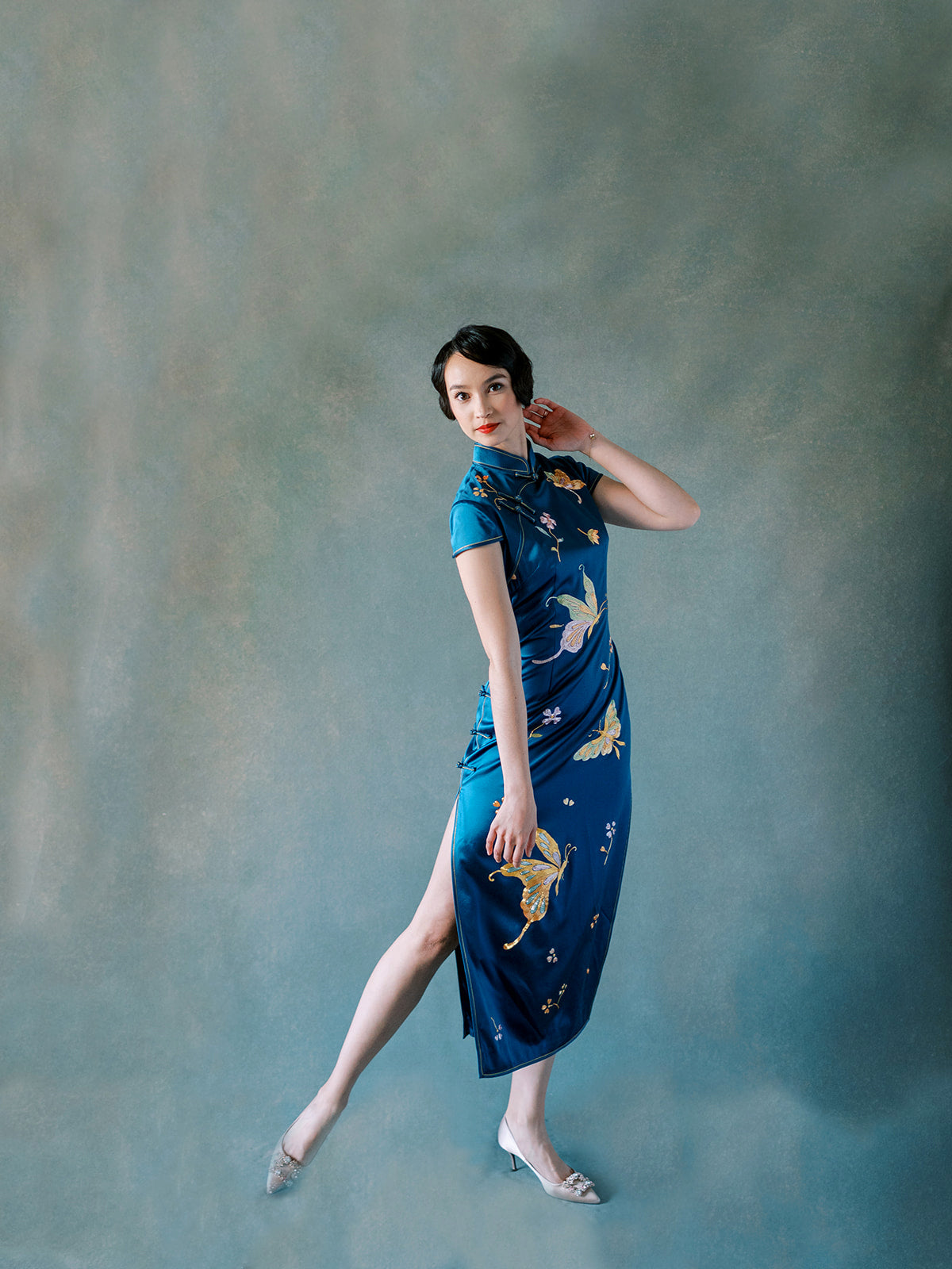 Side view of teal silk Qipao with hand-embroidered peonies and butterfly motif.