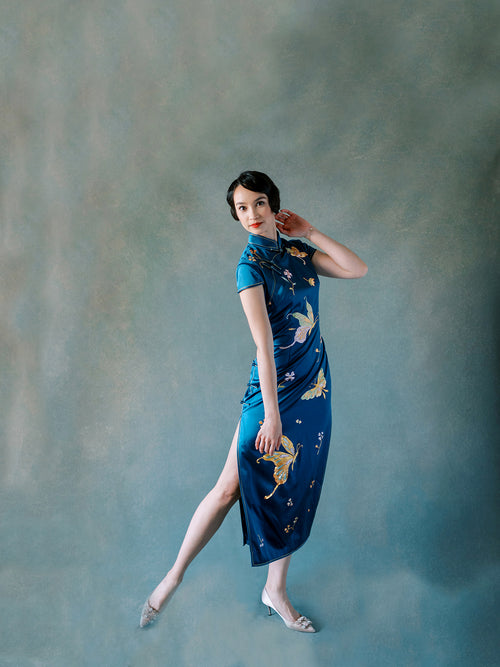 Side view of teal silk Qipao with hand-embroidered peonies and butterfly motif.