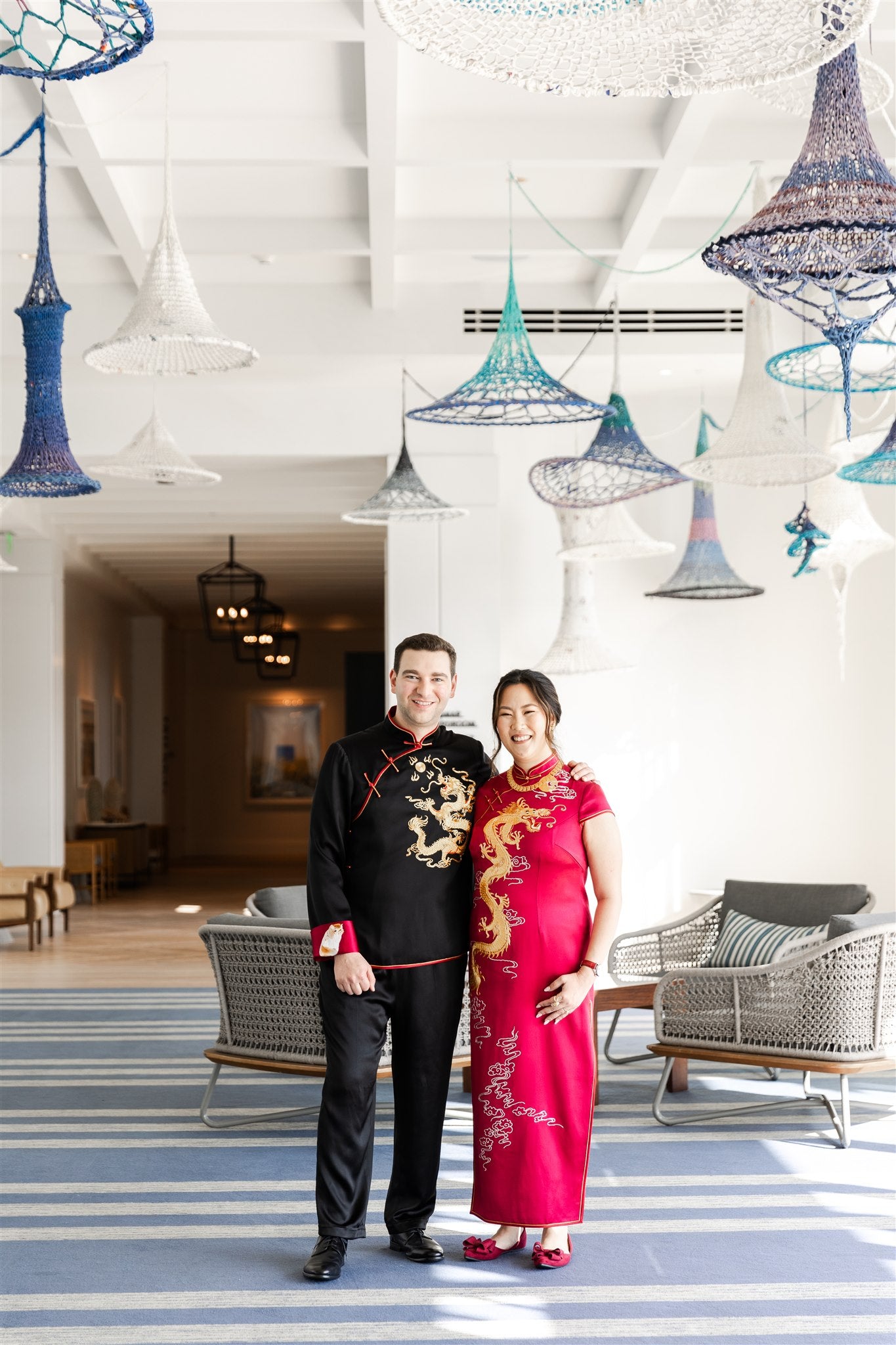 A couple is wearing matching red wedding qipao and black silk tang suit and silk pants