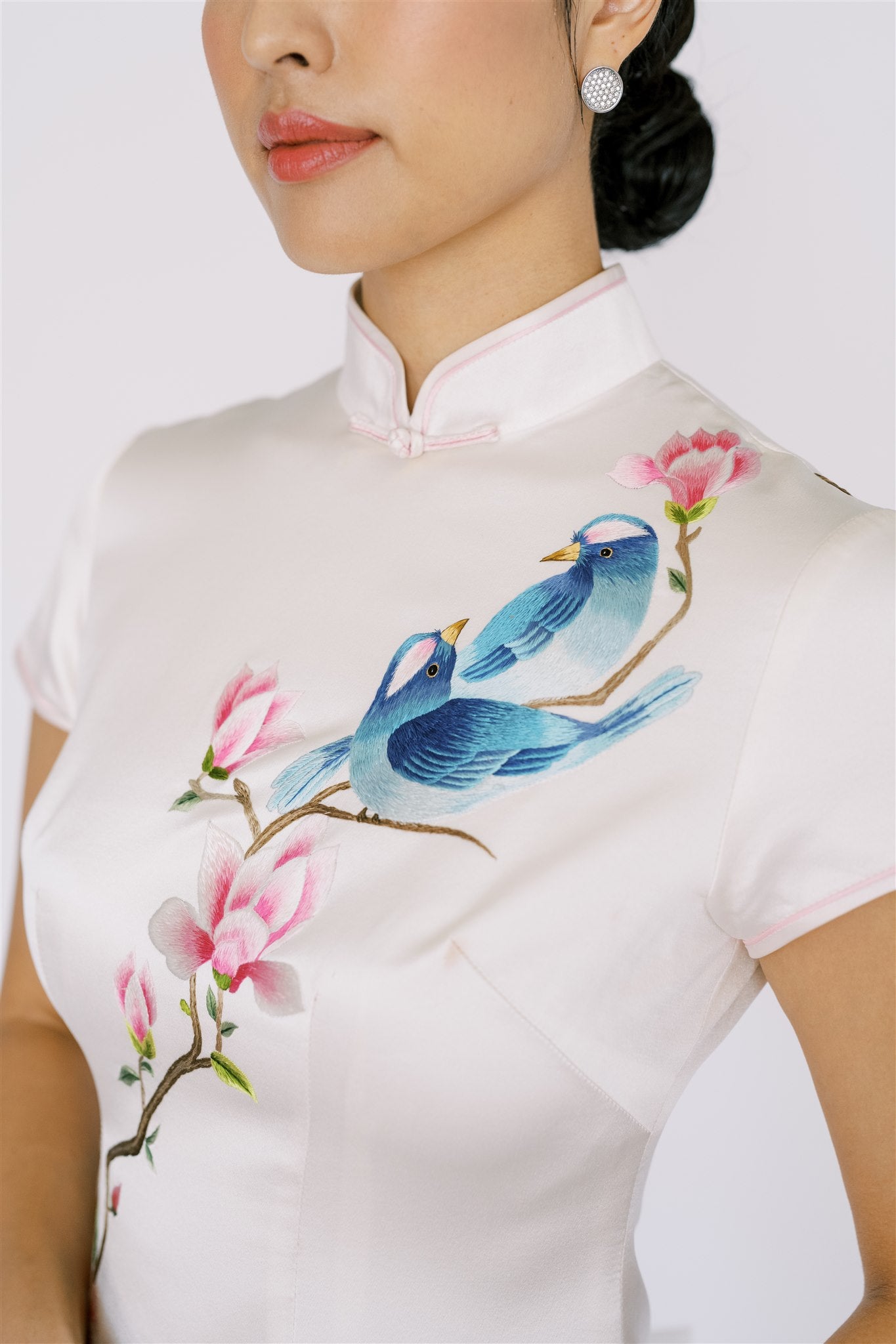 A woman wearing a white Qipao with bird embroidery