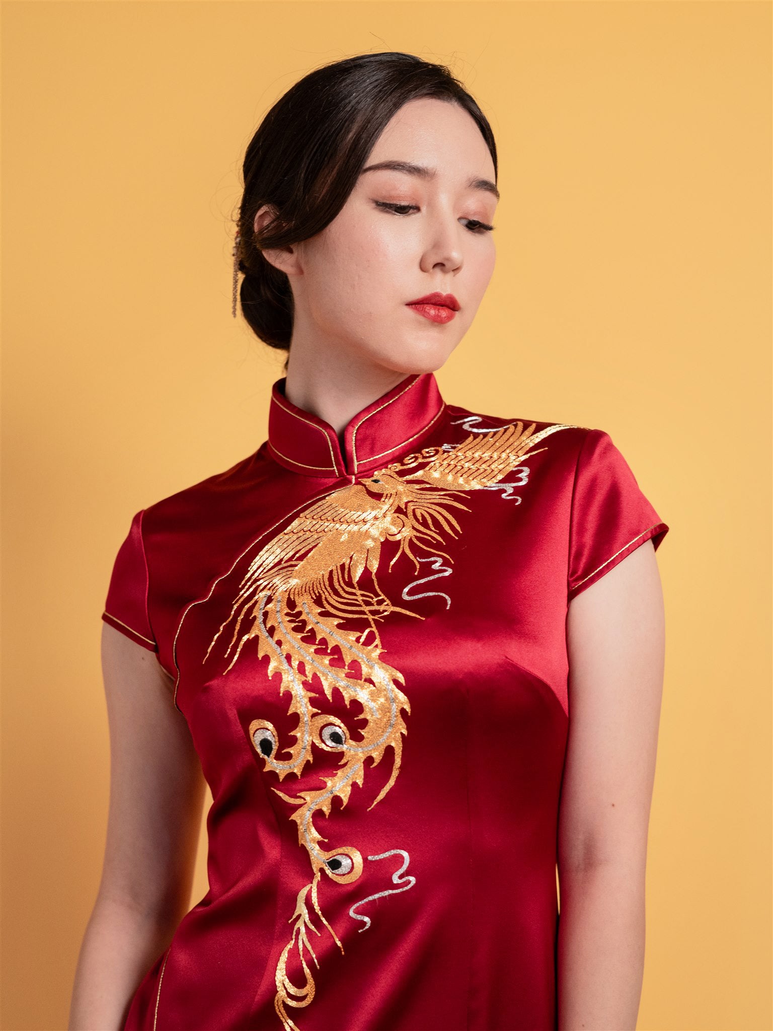 Close-up of gold phoenix embroidery on wine red Chinese wedding dress