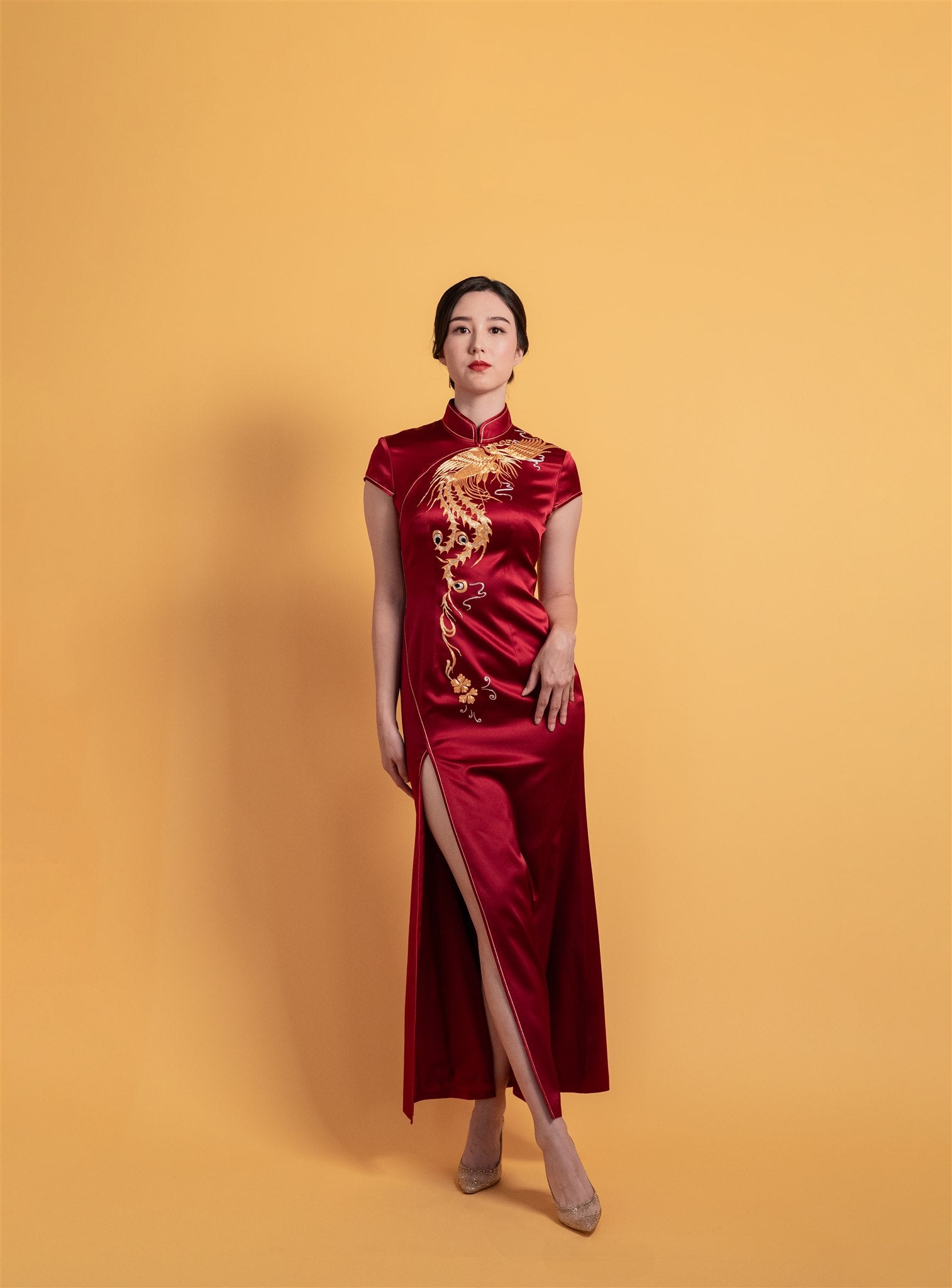 Front view of a wine red silk Chinese wedding Qipao with gold dragon and cloud embroidery, mermaid silhouette, and front slit by JINZA.