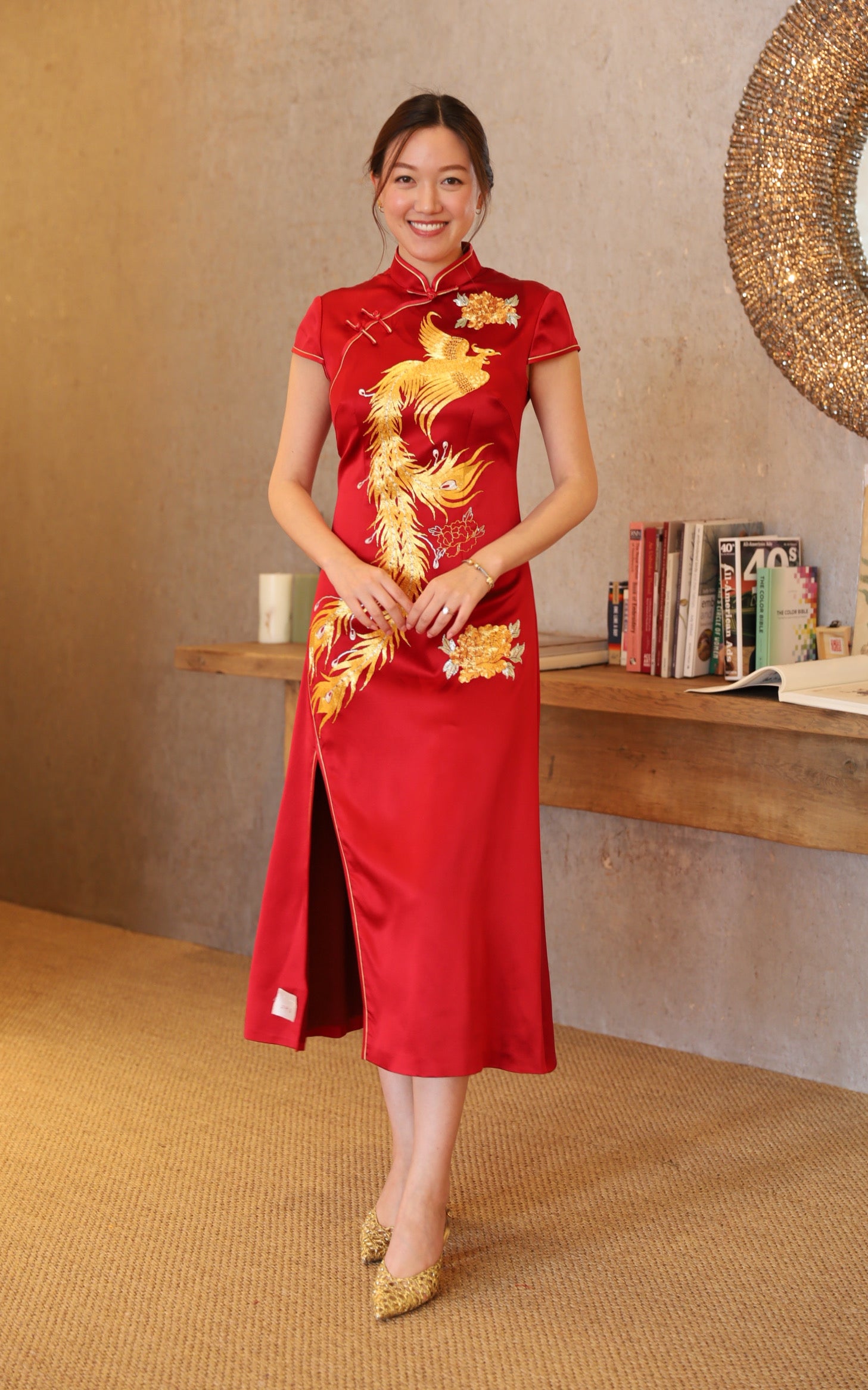 A woman wearing a wine red mermaid Qipao with phoenix and peonies embroidery