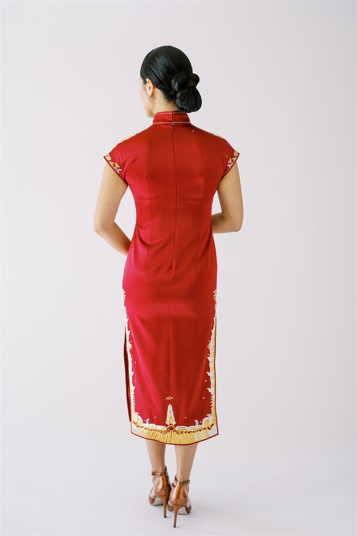 A woman wearing a wine red wedding Qipao with gold embroidery